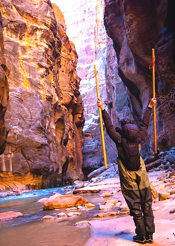 Roxanne standing confidently with hiking stick at The Narrows in Utah, symbolizing empowerment and resilience