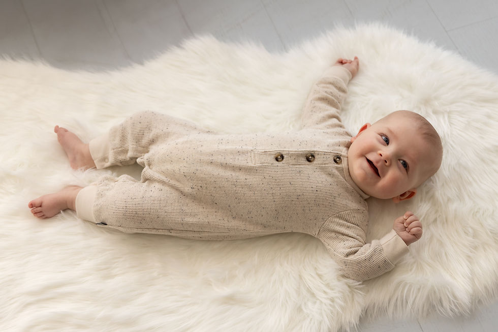 The happy baby smiles and lays on the perfect neutral colors for milestone photography.