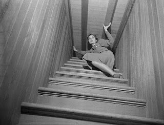 A woman shown on the stairs that lead to the ceiling - via Unhinged Historian