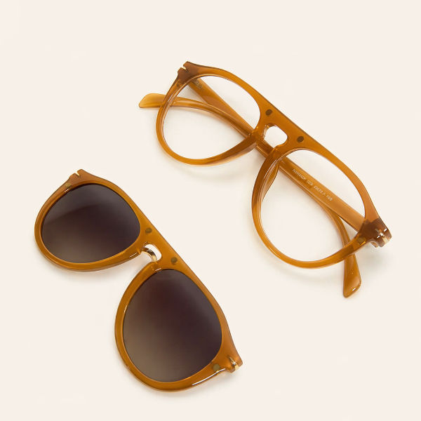 Óculos de grau Smart em acetato translúcido âmbar e óculos de sol Smart com lentes degradê posicionados lateralmente.