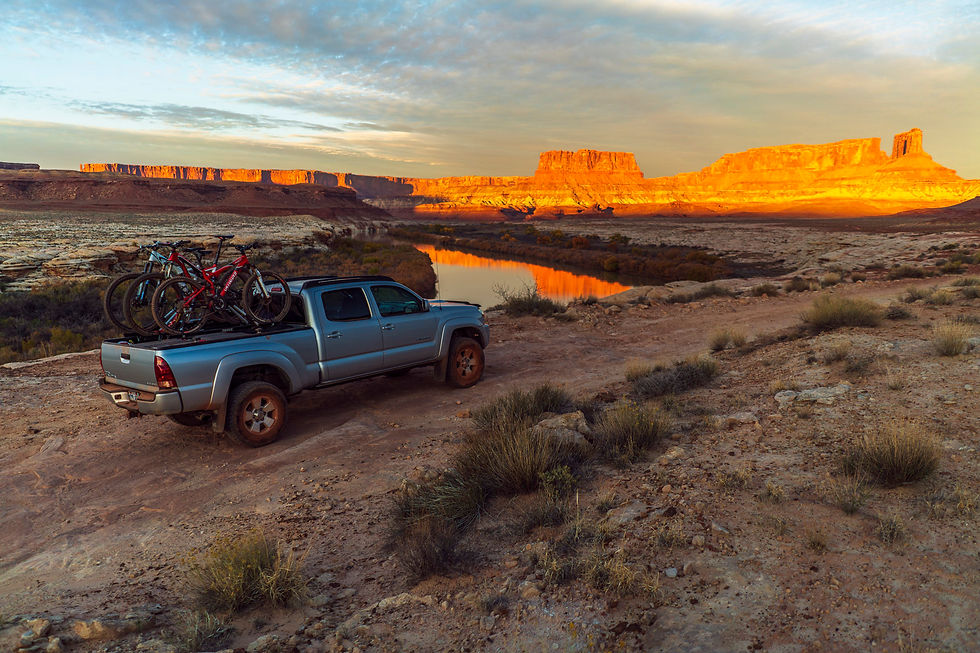 A Toyota Tacoma truck product image in the outdoors with a sun setting on a red rock backdrop.