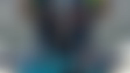 E1 Team Miami racers standing on their electric race boat holding helmets, wearing blue and orange team suits.