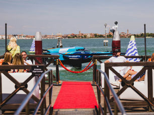 E1 Team Miami RaceBird returning to the dock in Venice after competition, with spectators and historic buildings in the background.