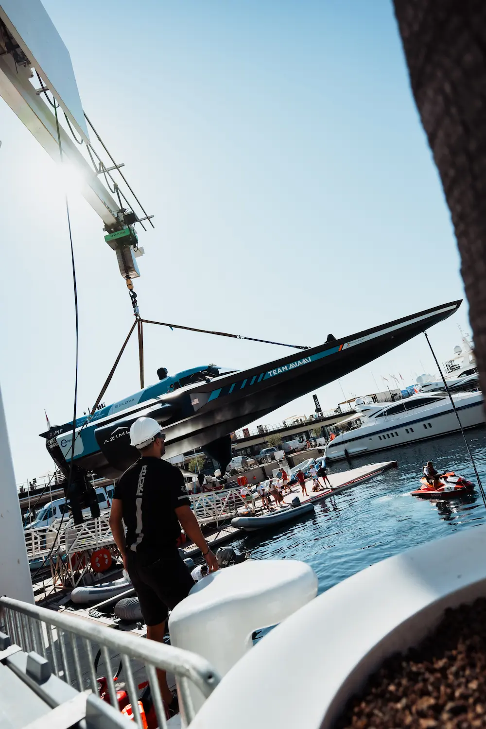 E1 Team Miami electric raceboat being hoisted over the Monaco marina as spectators watch from the docks, highlighting the excitement of high-tech marine motorsport.