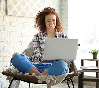 woman with redhair sitting in her apartment typing on her computer representing working on your therapist marketing
