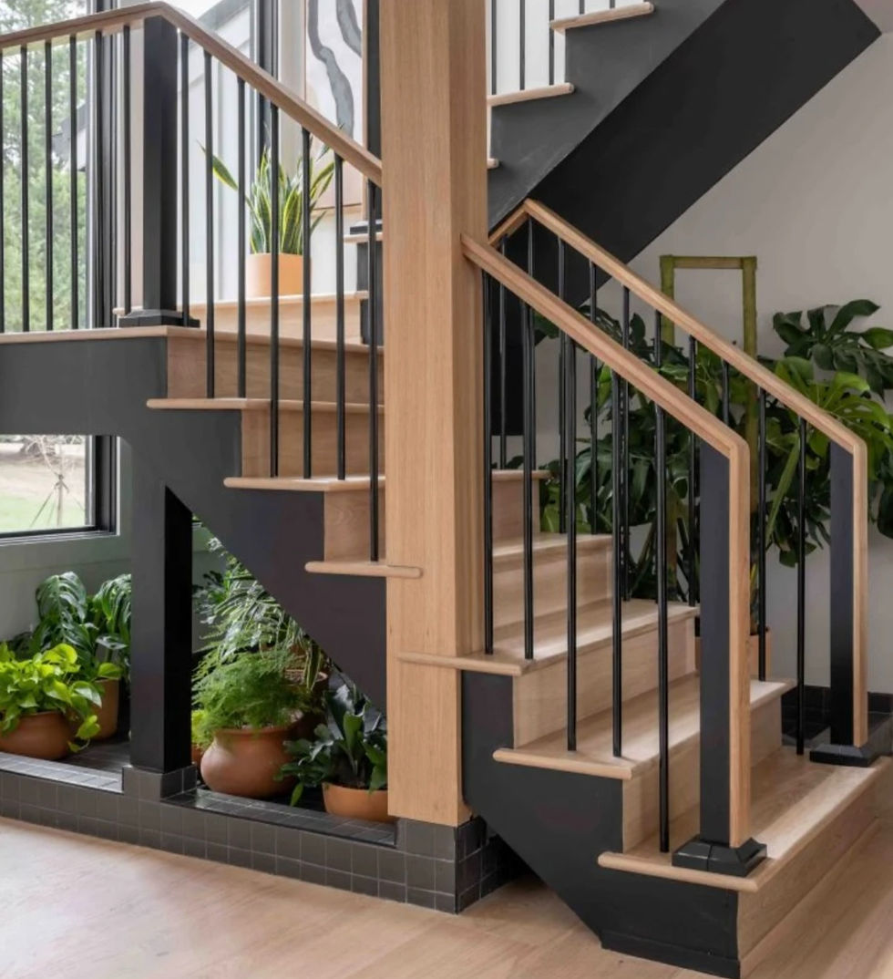 Modern indoor staircase with wood steps, black railings, and potted green plants in a bright, airy home.
