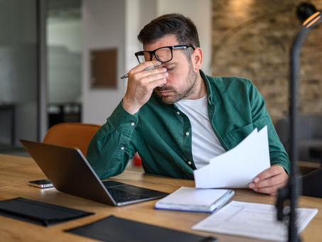 Frustrated Man Rubbing Eyes Looking at Laptop