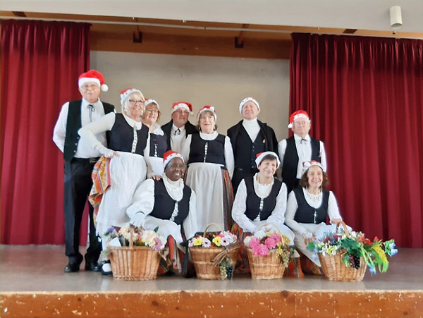 Membres du groupe portant des costumes et des chapeaux de Noël. Cazouls Noêl 2024. Sur scène, souriants.
