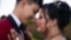 A couple in wedding attire shares an intimate forehead touch. The woman wears intricate henna and green jeweled earrings. Romantic mood.