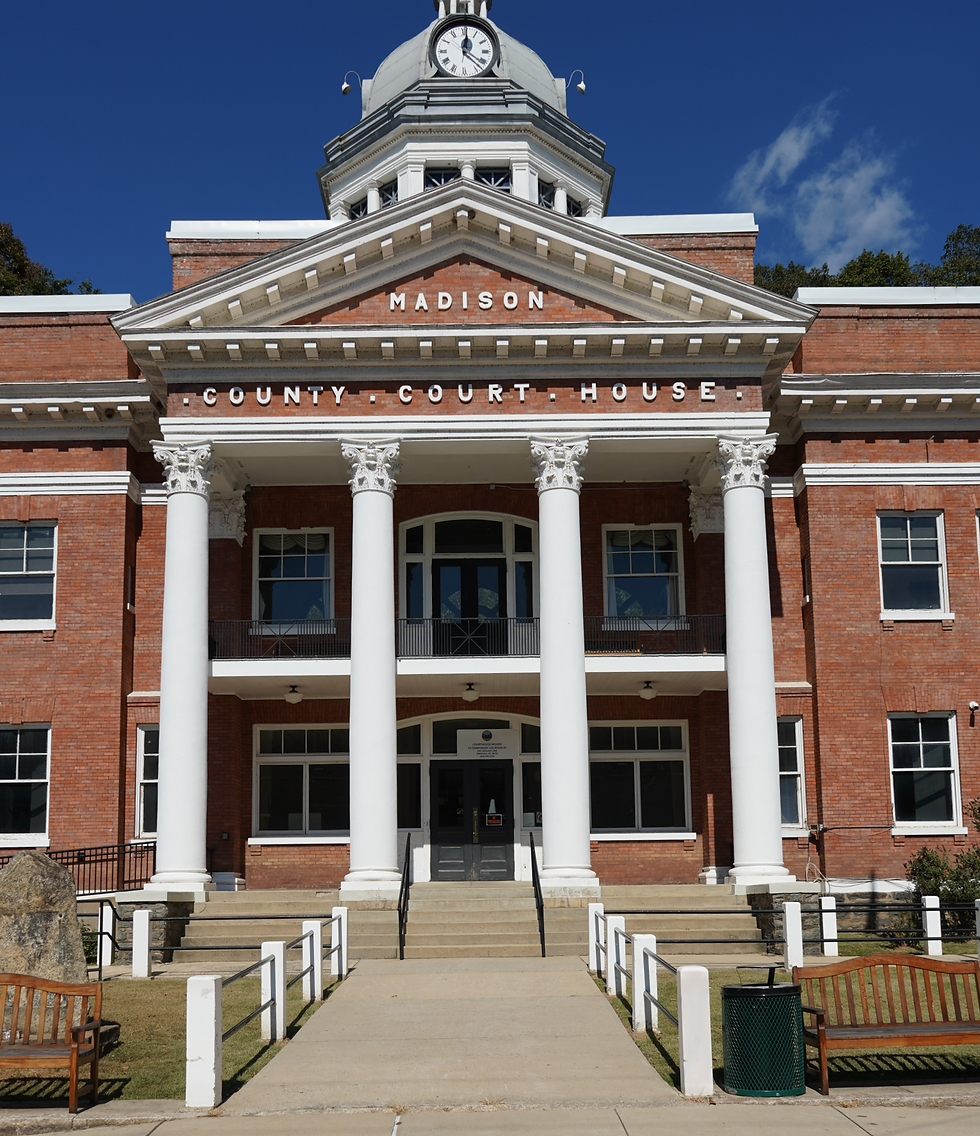 Madison County Courthouse with white columns and clock tower under a blue sky; sign reads MADISON COUNTY COURT HOUSE.