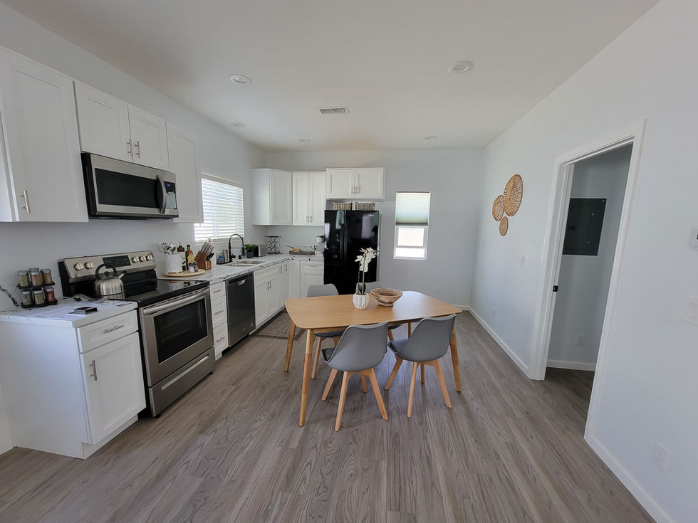 Open concept kitchen and dining room remodel featuring white cabinetry and durable wood-look flooring in San Diego.