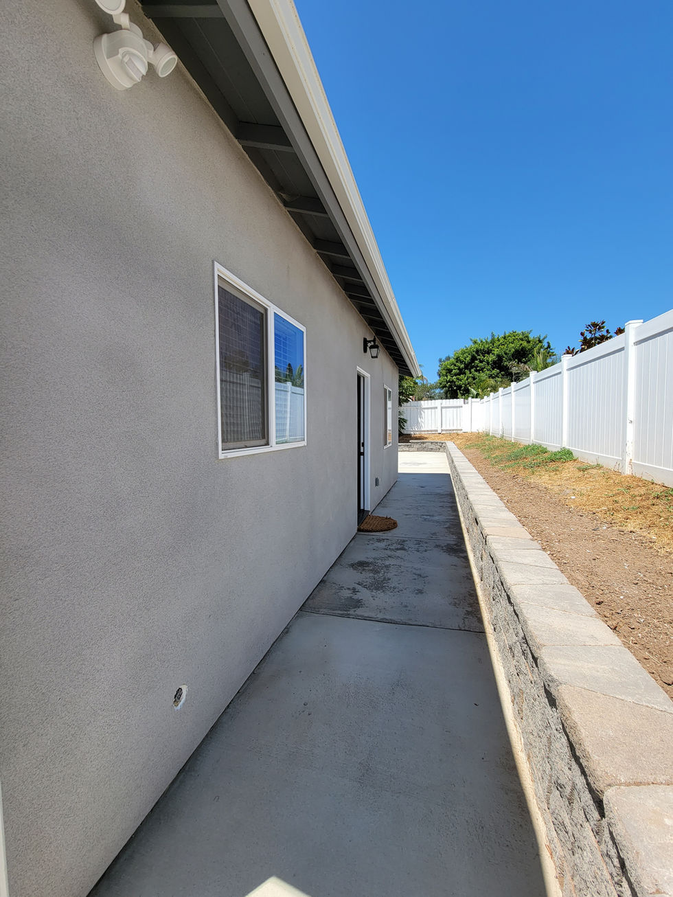 the side of a house with a white fence behind it