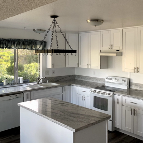 San Diego kitchen remodeling project featuring white cabinets, dark contrasting countertops, and a large center island.