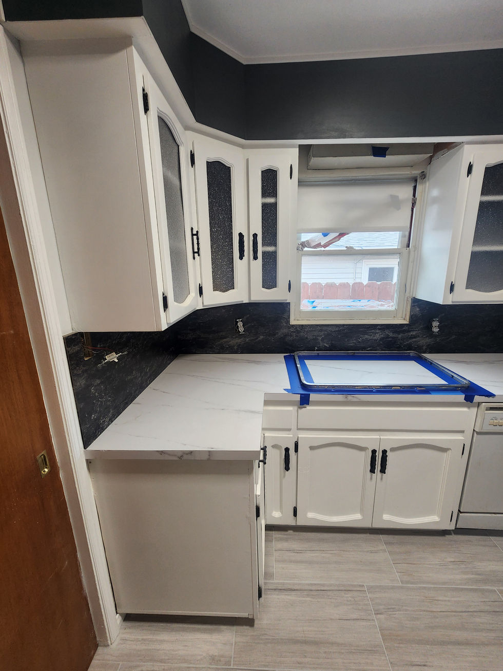 a kitchen with white cabinets and black counter tops