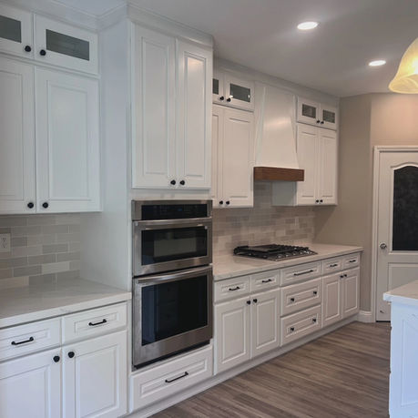Premium kitchen remodel with built-in double wall ovens and a custom wood-trim range hood in San Diego.