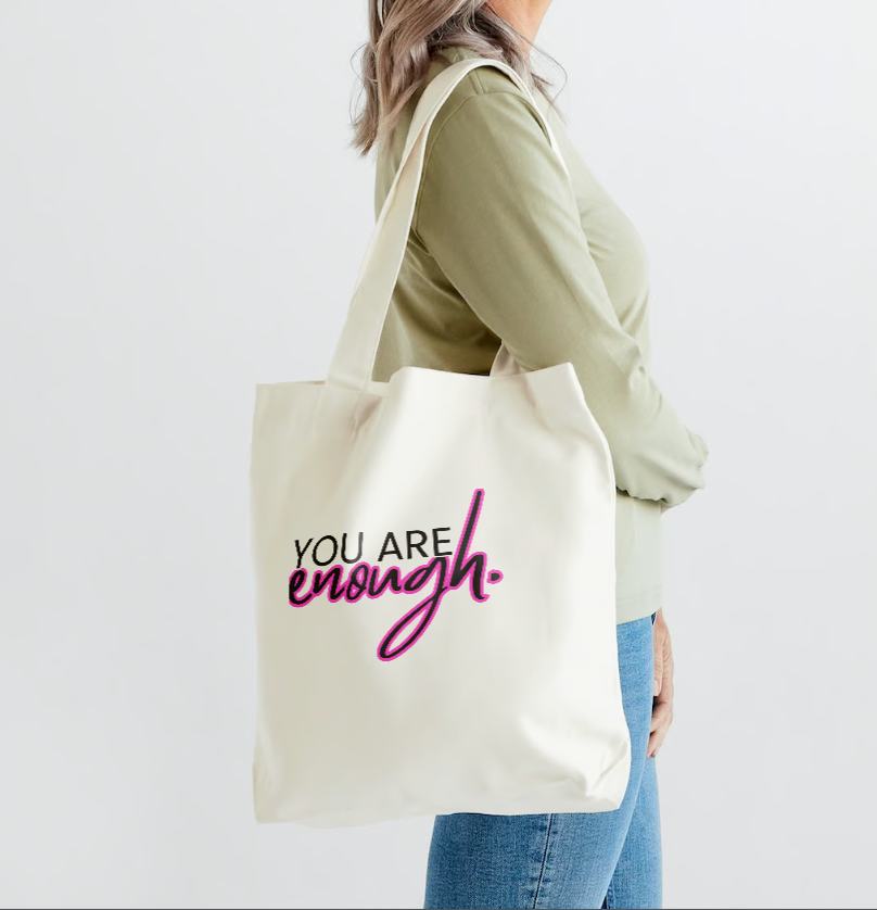 Girl wearing a tote bag that says You Are Enough in white