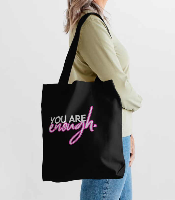 Girl wearing a tote bag that says You are enough in black