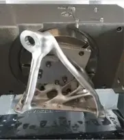 Charnière issue de la fabrication additive montée sur le centre d'usinage pour réaliser le post-traitement pour le projet Aile