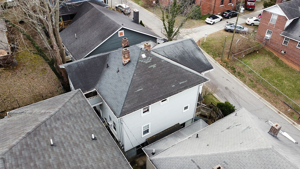 Aerial view of residential roof in Hendersonville NC with damaged shingles and repair patches