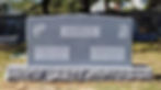 Gray granite companion headstone with engraved family name and custom carvings installed in a cemetery
