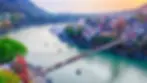The iconic Lakshman Jhula suspension bridge spanning the vibrant blue Ganges River in Rishikesh, surrounded by green hills, ashrams, and adventure sports, a renowned yoga retreat destination.