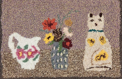 Handmade wool rag rug featuring a Staffordshire cat ornament, jug and vase of flowers.