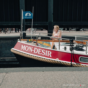 Straatfotografie van persoon of personen op een boot die onder een donkere brug door vaart in Sneek. Het zijn watersporters in Friesland.