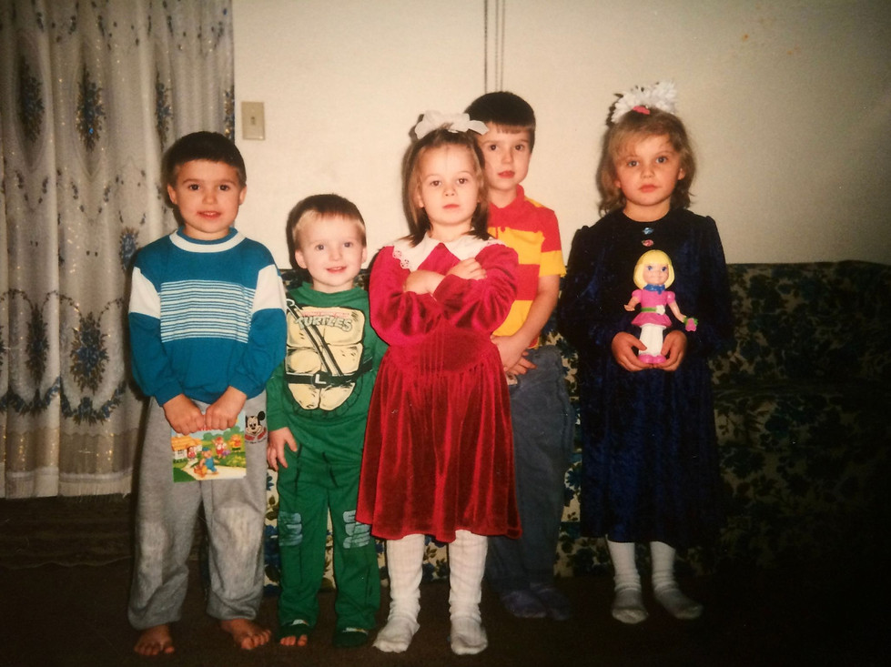 Viktoriya Volkov (center, in red dress) stands with arms crossed among fellow immigrant children, including her sister Anastasiya (right). The stance is more than childhood defiance—it’s a quiet readiness, a foreshadowing of the grit she’ll need to face the unraveling of Portland and the cracks in the promise of the West. Part of the photo archive for Ukrainian Monster: An American Story.