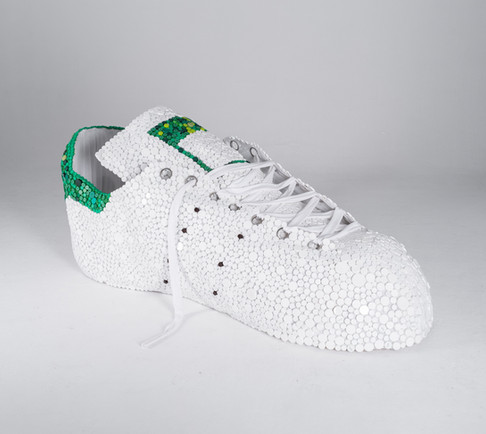 Large white and green sculpture of an Adidas Stan Smith sneaker made by Toronto artist Briony Douglas out of recycled bottle caps.