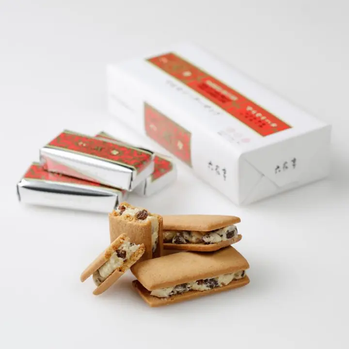 北海道伴手禮六花亭餅乾紅白相間的包裝盒，以及三塊焦黃色餅乾夾著白色奶油餡料