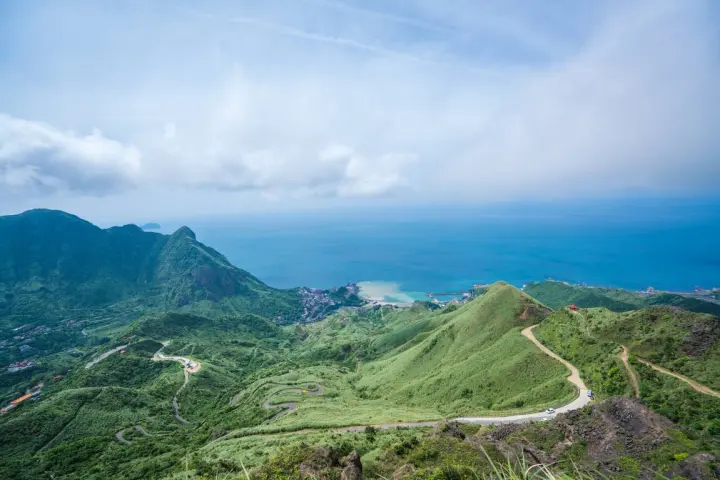 無耳茶壺山步道俯瞰視角：蜿蜒山路連結金瓜石山城，背景為遼闊藍天與療癒海景