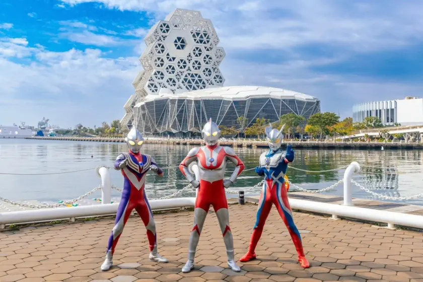 高雄燈會聯手知名 IP「超人力霸王」題，三個超人站在高雄流行音樂中心河岸邊合影