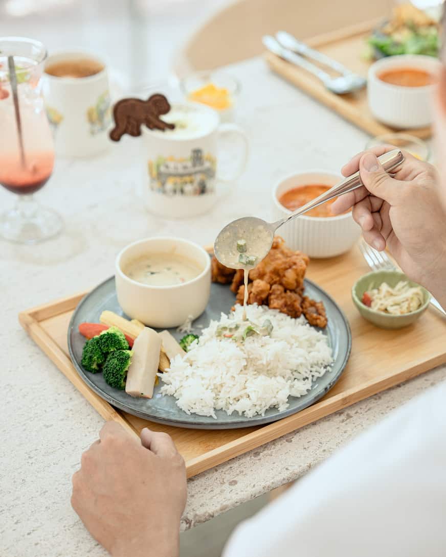 光室咖啡廳的唐揚雞套餐，木製餐盤上的藍色盤子放有裝滿米飯、青菜與濃湯和炸雞，桌子上還有杯掛著猩猩裝飾的飲料