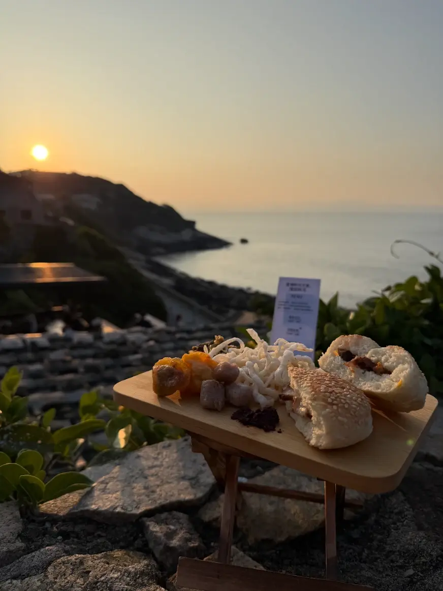 夕陽時分,海堤的石階上擺著木盤子,上面有馬祖繼光餅、地瓜餃、魚麵等食物