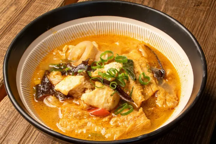 木桌上擺有一碗配料豐富的砂鍋魚頭料理