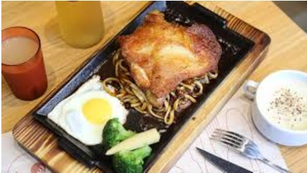 萬國牛排餐點煎雞腿、義大利麵、煎蛋和西蘭花，旁邊有兩杯飲料和一碗湯，