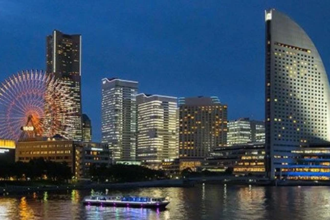  橫濱水上巴士行駛於港未來夜色中，背景為燈火通明的摩天輪與摩天大樓