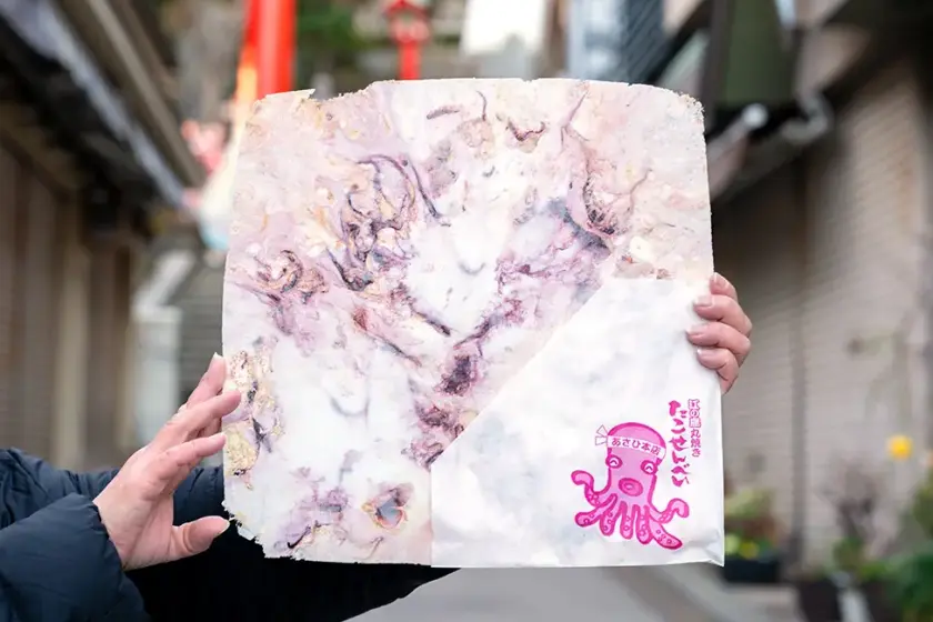 江之島必吃打卡美食「章魚仙貝」，米白色的仙貝上有紫色章魚壓紋