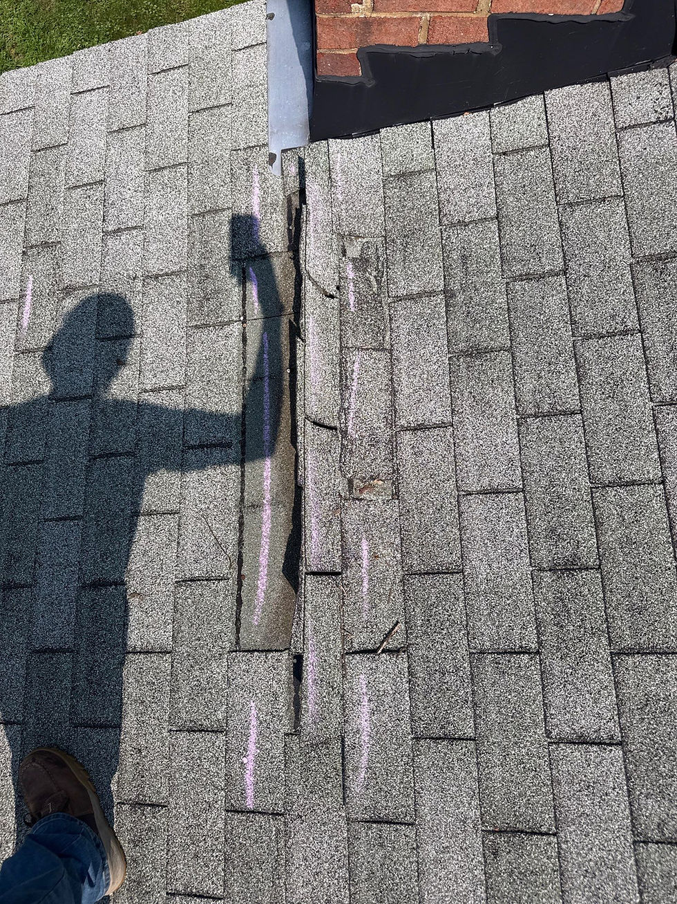 Roofing technician marking storm-damaged shingles during a roof inspection in Maryland