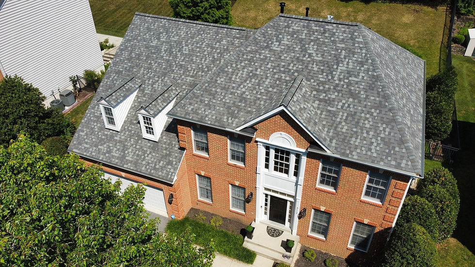 Aerial view of a finished asphalt shingle roof replacement on a brick colonial home in Maryland