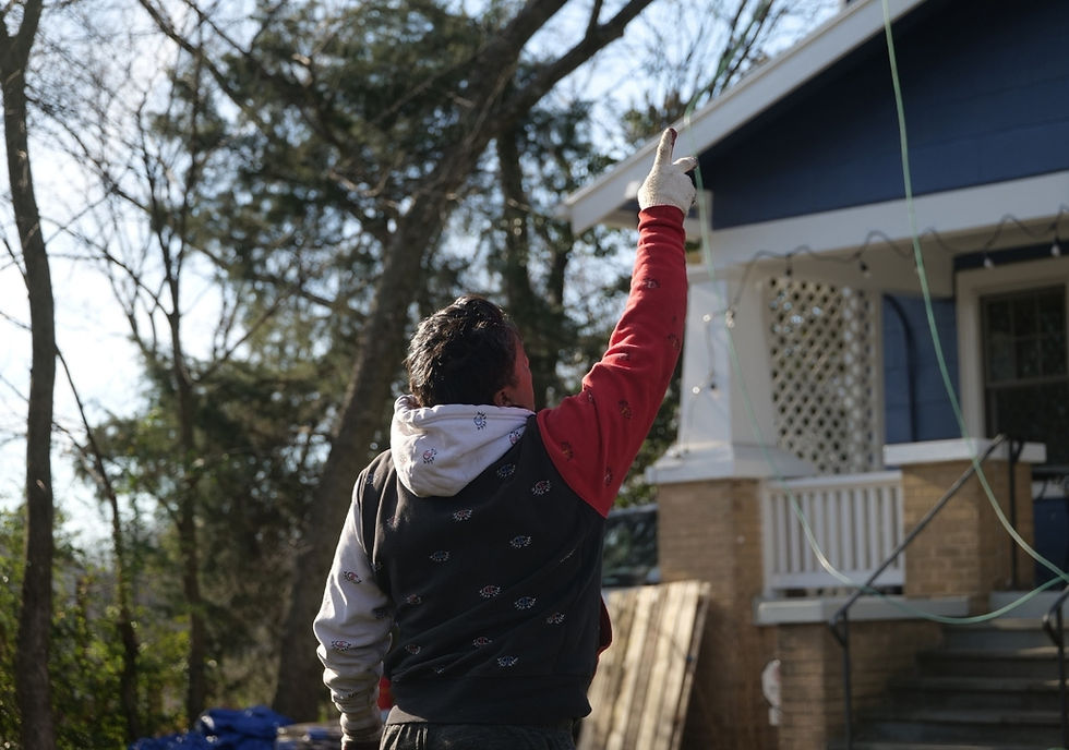 Restoration Roofing Co. crew member pointing to the roof of a blue-sided home in Maryland