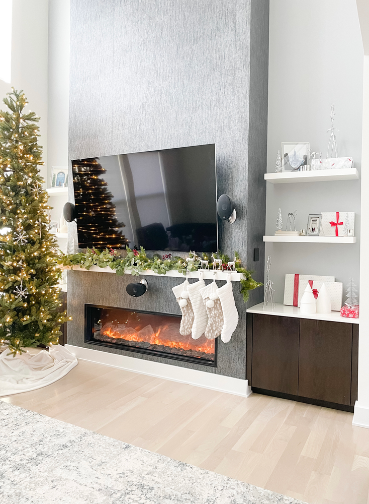 Looking to create a modern mantel with red, white and silver! Recreate this modern look by adding faux pine, eucalyptus, berries and twinkle lights. Add neutral stocking, packages with red ribbon and you have the perfect holiday mantel and shelves! #redandwhiteholiday #redandwhitechristmas #christmasmantel