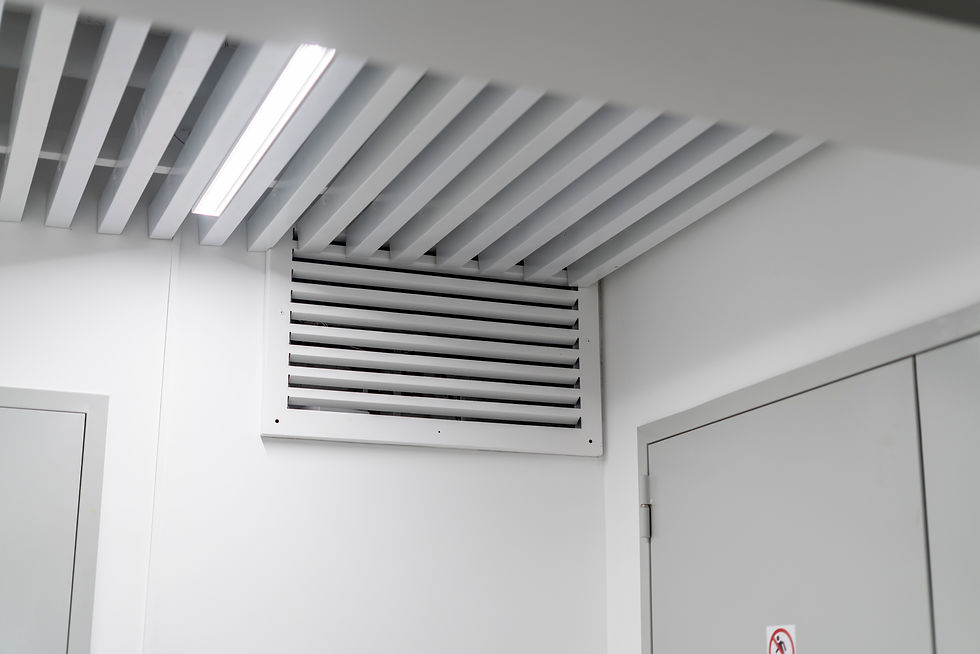 White hallway ceiling with slatted vents and a fluorescent light above two gray doors, one with a no-smoking sign.