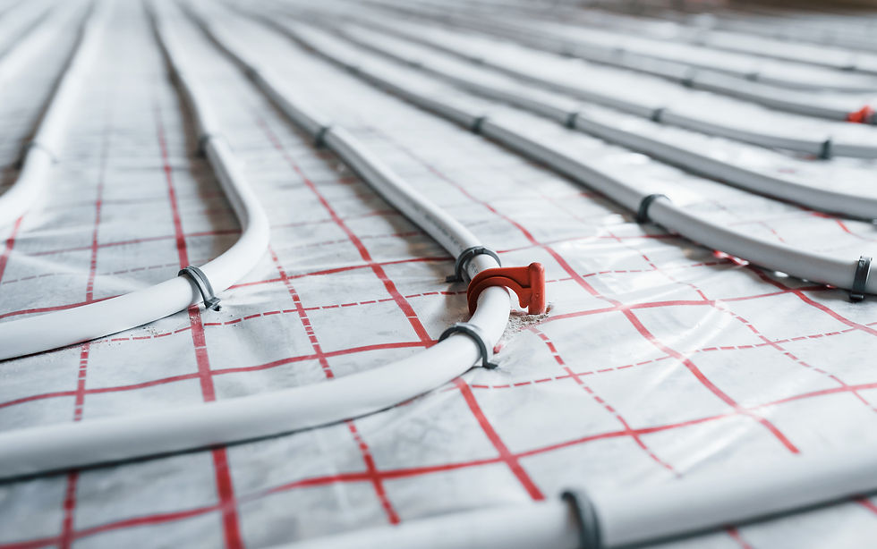 White underfloor heating pipes laid in red grid insulation, secured with clips, in a clean construction setting.