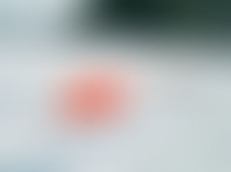 Two orange hard hats and a tape measure on a white metal roof, with trees in the blurred background under a blue sky.