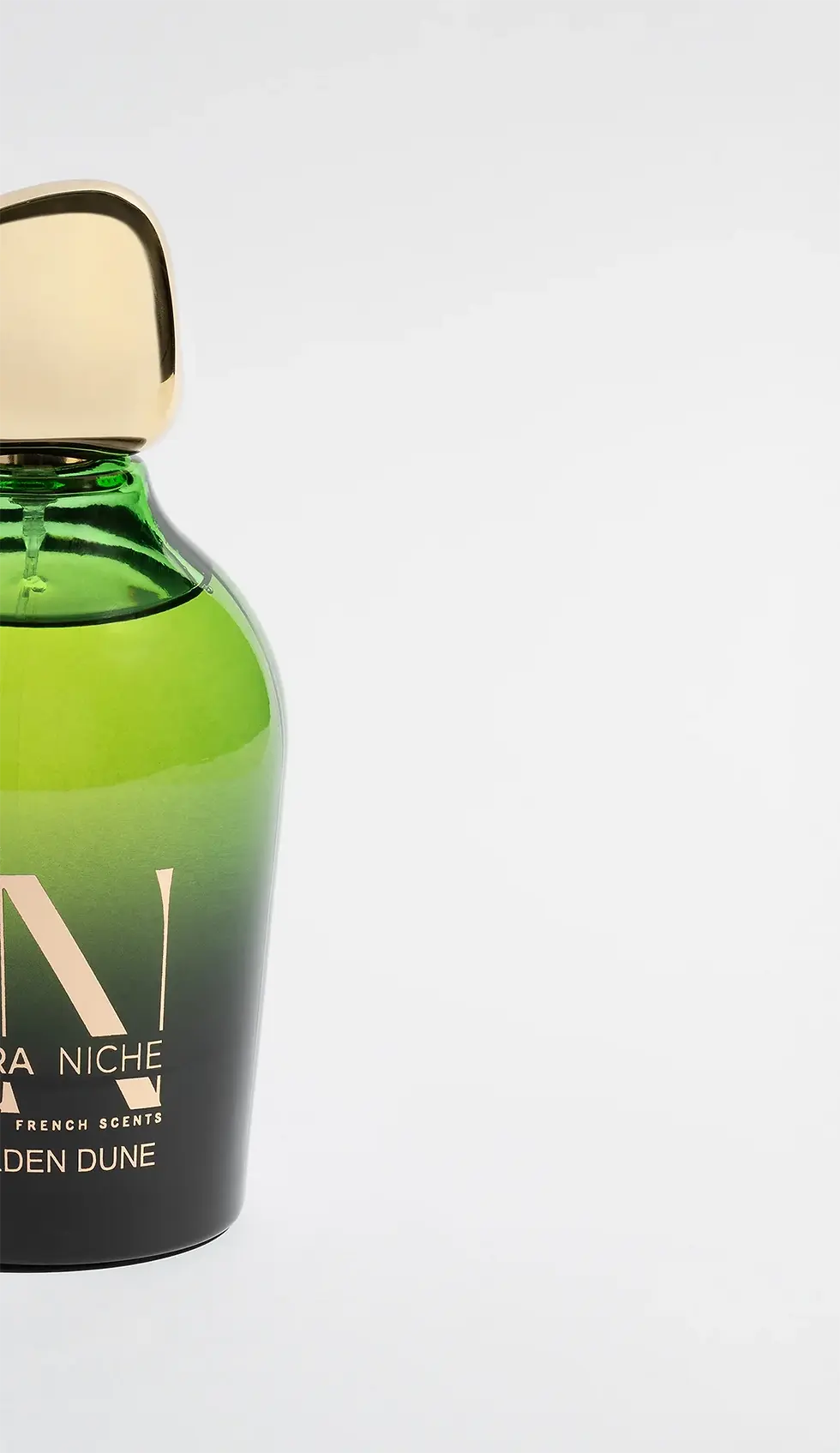 Close-up of Ultra Niche Golden Dune perfume bottle - gradient green glass with gold embossed branding, designed by Identiscents, high-end fragrance packaging manufacturer in the Middle East.