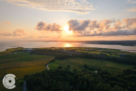 Drone photo of a vibrant sunset over a seaside park and golf course