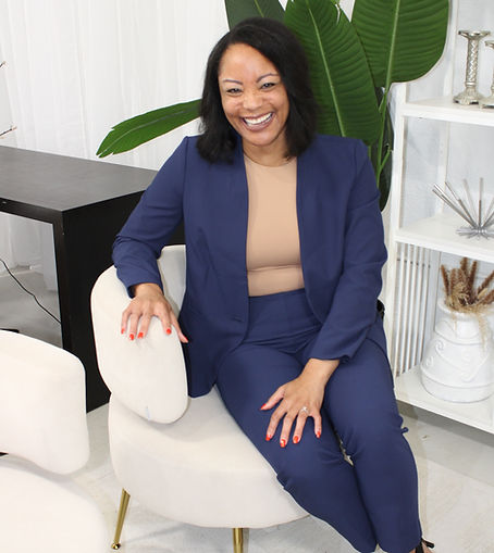 Angie Edmonds, founder of Edmonds Law Firm, sitting on a white chair wearing a navy suit, smiling after talking to her clients about her healthcare compliance services
