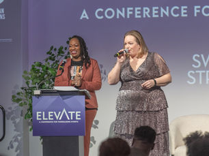 Benefit auctioneer Kelly Russell of Artisan Auctions speaks on stage next to an event emcee at a podium