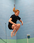 Young gymnast, performing tuck jump on trampoline